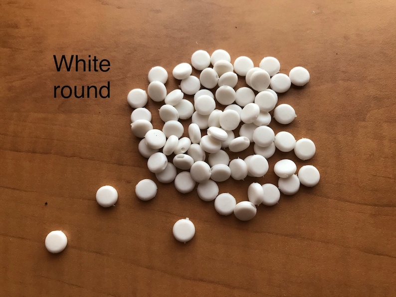 May include: A pile of white round plastic buttons. The buttons are about 1/2 inch in diameter.