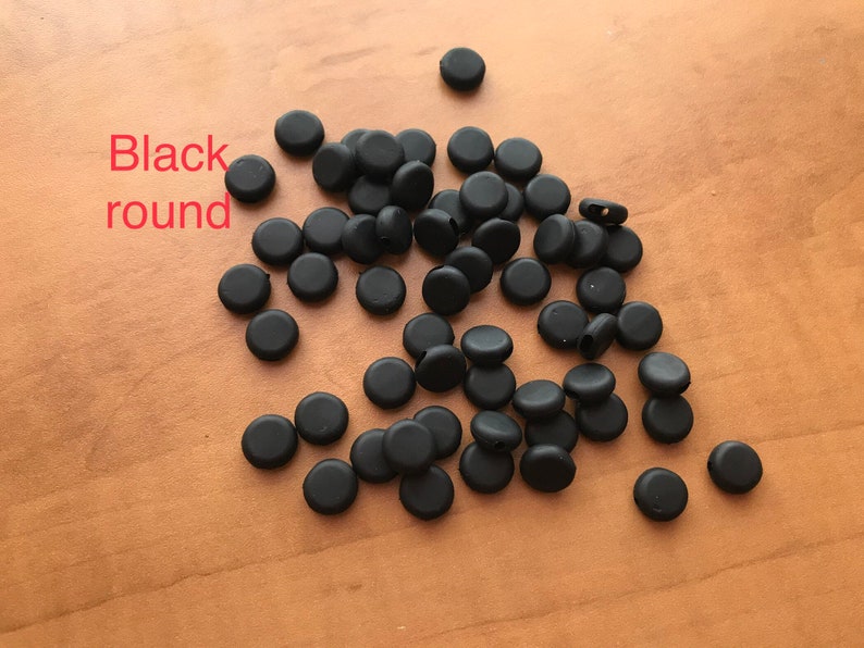 May include: A pile of black round rubber stoppers.