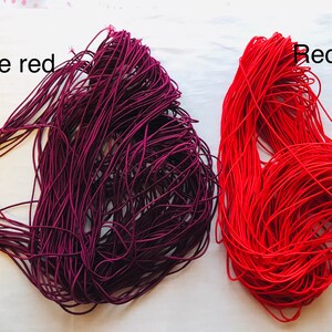 May include: Two spools of elastic cord, one in wine red and one in red. The spools are labeled "Wine red" and "Red".