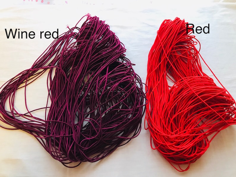 May include: Two spools of elastic cord, one in wine red and one in red. The spools are labeled "Wine red" and "Red".