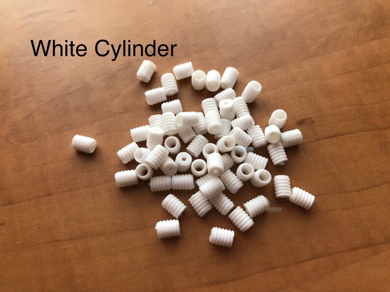 May include: A pile of white plastic cylinder cord ends.