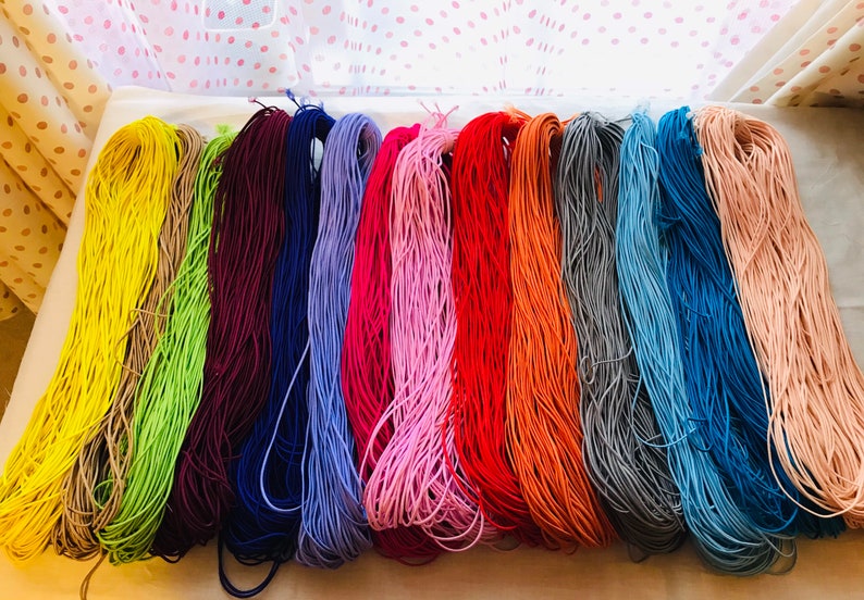 May include: A collection of 12 spools of colorful elastic cord. The colors are yellow, beige, green, burgundy, navy blue, lavender, pink, red, orange, gray, light blue, and peach.