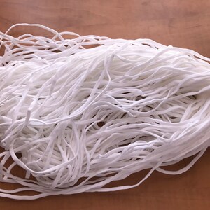 May include: A large pile of white elastic cord, ideal for crafting projects.