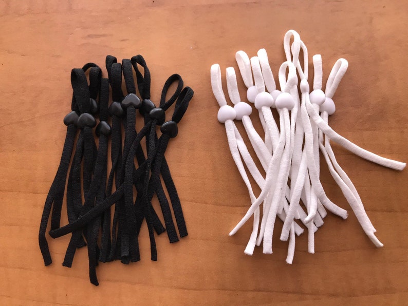 May include: A set of 10 black and 10 white elastic mask extenders with adjustable toggles. The toggles are heart-shaped on the black extenders and round on the white extenders.
