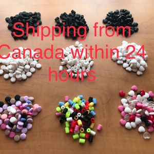 Könnte beinhalten: Sortiment an bunten Silikon-Ohrstöpsel-Spitzen in verschiedenen Formen, darunter rund, herzförmig und zylindrisch. Die Spitzen sind in Stapeln auf einer Holzoberfläche angeordnet.