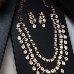 Puede incluir: Un conjunto de collar y pendientes de oro con una doble hilera de piedras transparentes en forma de l&aacute;grima y hexagonales.