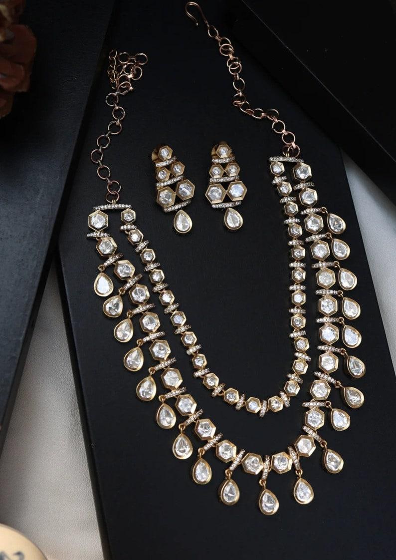 Puede incluir: Un conjunto de collar y pendientes de oro con una doble hilera de piedras transparentes en forma de l&aacute;grima y hexagonales.