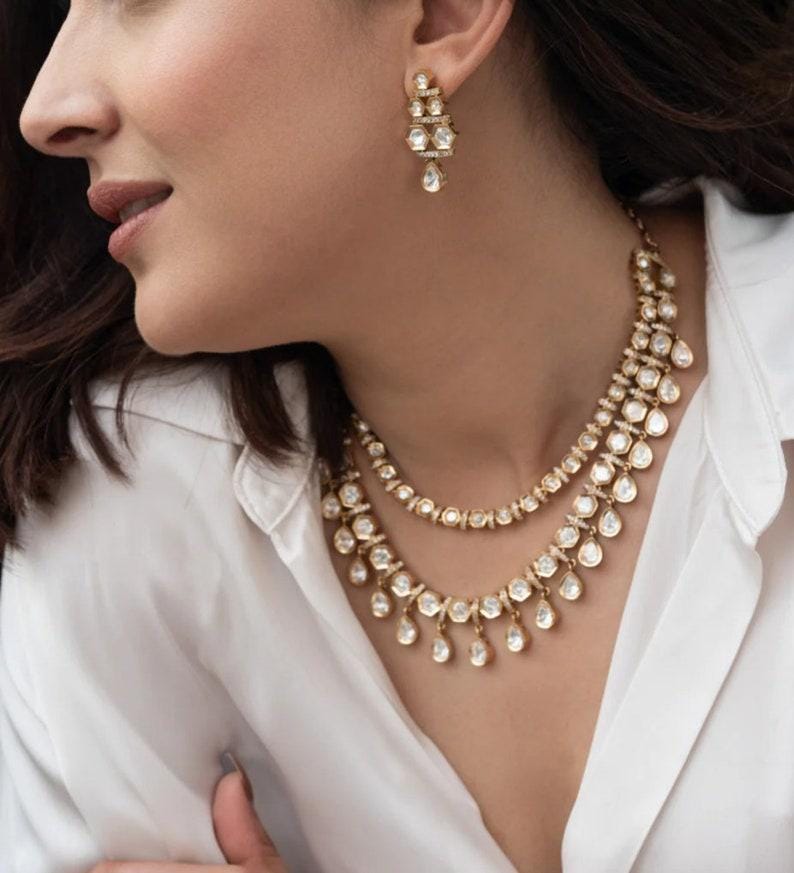 Puede incluir: Un collar de oro con una doble fila de piedras en forma de l&aacute;grima y una fila m&aacute;s peque&ntilde;a de piedras redondas. El collar lo lleva una persona con el pelo oscuro. La persona tambi&eacute;n lleva pendientes de oro con piedras en forma de l&aacute;grima.