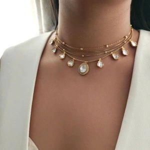Peut inclure: Un collier ras de cou à plusieurs rangs en or avec plusieurs pendentifs en forme de goutte d'eau sertis de strass transparents.