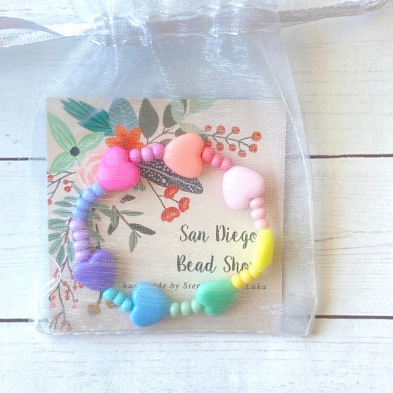 May include: A rainbow heart-shaped bead bracelet with a tag that says "San Diego Bead Shop" and "Handmade by Sierra Luka".