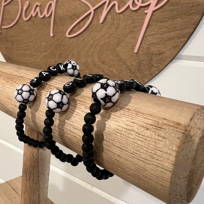 May include: Three black beaded bracelets with soccer ball charms and letter beads spelling out the names "JACK", "OLIVER", and "RYAN".