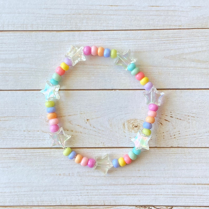 May include: A rainbow-colored beaded bracelet with iridescent star-shaped charms. The bracelet is made with small, round beads in shades of pink, yellow, green, blue, and purple.