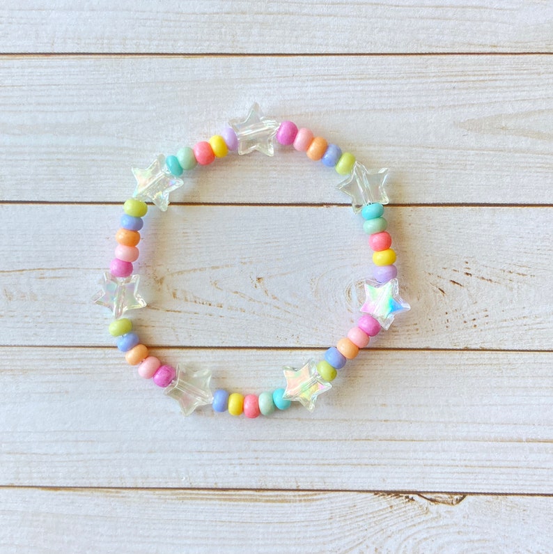 May include: A colorful beaded bracelet with iridescent star-shaped charms. The bracelet is made with pastel pink, yellow, blue, and green beads.