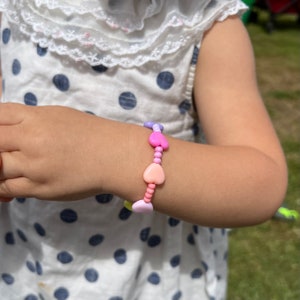 May include: A colorful heart-shaped beaded bracelet with pink, purple, and light blue beads.