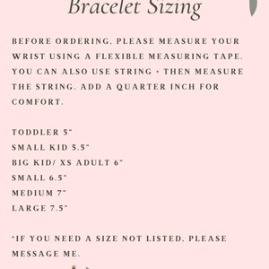 Puede incluir: Un gr&aacute;fico rosa y blanco con acentos florales proporciona instrucciones para medir el tama&ntilde;o de la mu&ntilde;eca para pulseras. El texto dice: "Bracelet Sizing" e incluye informaci&oacute;n de tallas para ni&ntilde;os peque&ntilde;os, ni&ntilde;os peque&ntilde;os, adultos y mu&ntilde;ecas grandes. El texto tambi&eacute;n dice: "Antes de ordenar, mida su mu&ntilde;eca con una cinta m&eacute;trica flexible. Tambi&eacute;n puede usar una cuerda + luego medir la cuerda. Agregue un cuarto de pulgada para mayor comodidad."