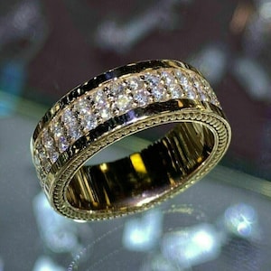 May include: A gold band ring with two rows of small, clear diamonds. The ring has a textured design on the outer edge.