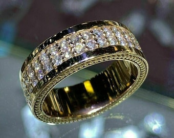 Könnte beinhalten: Ein Goldring mit zwei Reihen kleiner, klarer Diamanten. Der Ring hat ein strukturiertes Design am Außenrand.