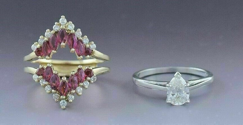 Puede incluir: Dos anillos de compromiso, uno con un diamante en forma de pera y el otro con un engaste de diamantes y rub&iacute;es. El anillo de rub&iacute; es un anillo de doble aro con un dise&ntilde;o de diamantes y rub&iacute;es.