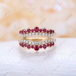May include: A gold ring with a row of small red gemstones and a row of small clear gemstones. The ring is designed to be worn as a wedding band or engagement ring.