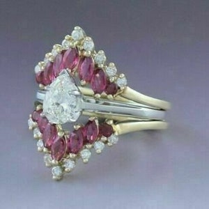 Puede incluir: Un anillo de compromiso de diamante de forma de pera engastado con un halo de peque&ntilde;os diamantes y una banda de rub&iacute;es.