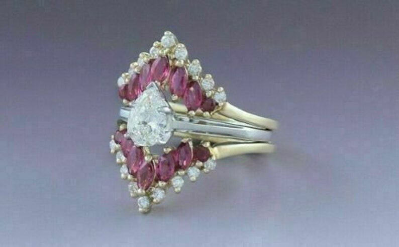 Puede incluir: Un anillo de compromiso de diamante de forma de pera engastado con un halo de peque&ntilde;os diamantes y una banda de rub&iacute;es.
