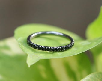 May include: A thin silver band ring with a row of small black gemstones.