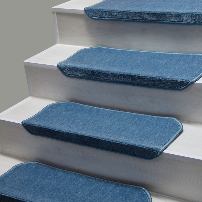 K&ouml;nnte beinhalten: Vier blaue Teppich-Treppenstufen mit einer strukturierten Oberfl&auml;che. Die Stufen sind auf wei&szlig;en Holztreppen platziert.