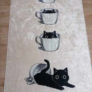 May include: A white background with a black cat peeking out of a coffee cup. The cat is in three different stages of emerging from the cup, starting with just its head, then its head and shoulders, and finally the whole cat is out of the cup.