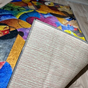 May include: A colorful abstract rug with a geometric design. The rug has a beige backing with a textured pattern.