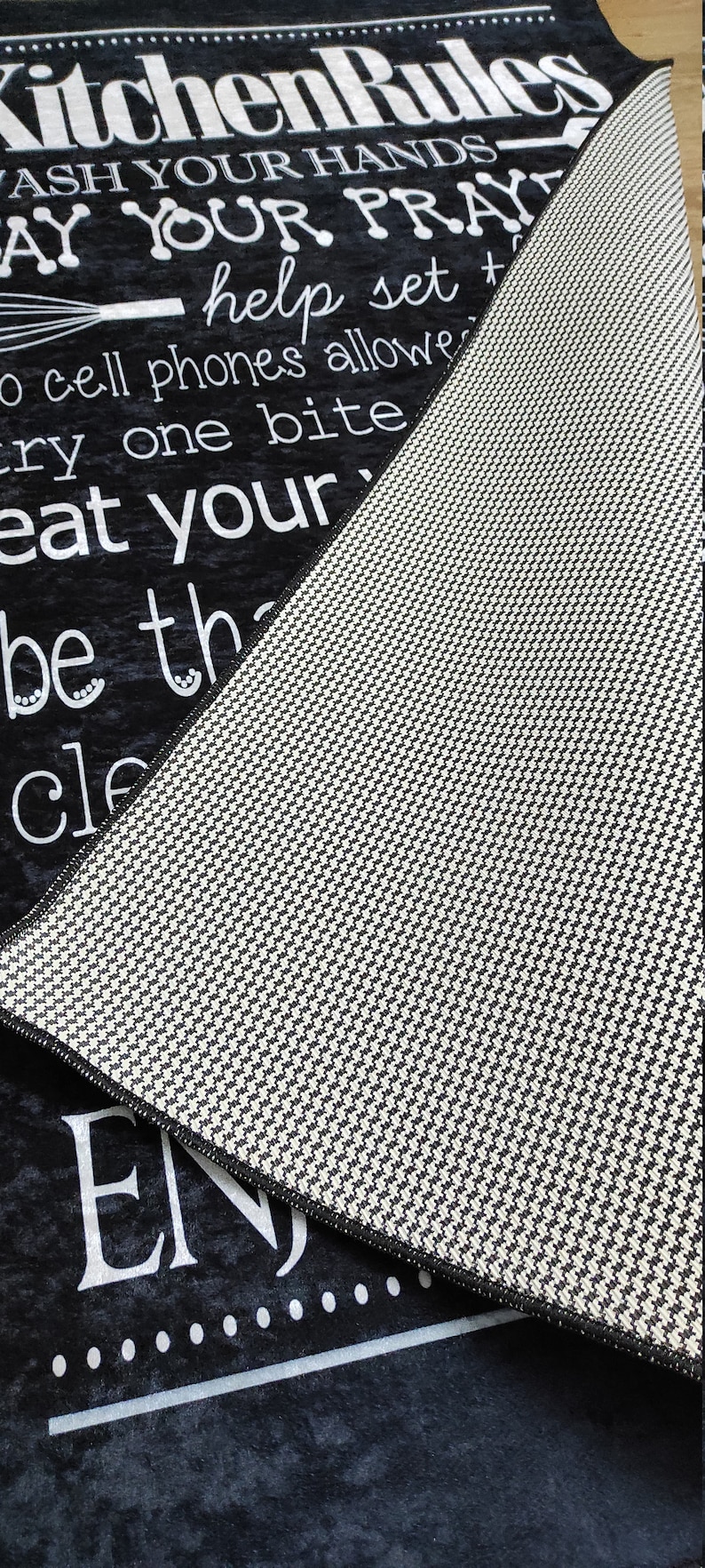 May include: Black and white kitchen rug with the text "Kitchen Rules" and a list of rules including "Wash your hands", "Say your prayers", "Help set the table", "No cell phones allowed", "Try one bite", "Eat your veggies", "Be the best you can be", "Clean up after yourself", and "Enjoy".