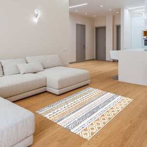May include: A white sectional sofa with a patterned rug in shades of brown, white, and gray. The rug has a geometric design with stripes and diamonds.