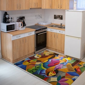 May include: A colorful abstract rug with a geometric design featuring a woman's face and a musical instrument. The rug is in a kitchen with white cabinets and a stainless steel oven.