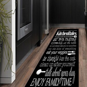 May include: Black and white kitchen rug with the text "Kitchen Rules" and a list of rules for family mealtime, including "Wash your hands", "Say your prayers", "Help set the table", "No cell phones allowed, no exceptions", "Try one bite of everything", "Eat your veggies", "Be thankful", "Kiss the cook", "Clean up after yourself", "Talk about your day", and "Enjoy family time".