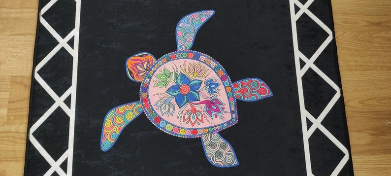 May include: A black rectangular rug featuring a colorful sea turtle design. The turtle has a pink shell with floral and geometric patterns. The border has a white geometric design. The rug is suitable for home decor.