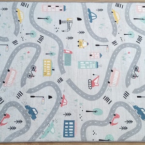 May include: A gray and white play mat with a city street design. The mat features winding roads, cars, trucks, bicycles, and buildings.