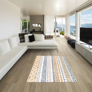 May include: A white sectional sofa with multiple pillows sits in a modern living room with large windows overlooking a mountain view. A patterned rug in shades of brown, gray, and white is on the floor in front of the sofa.