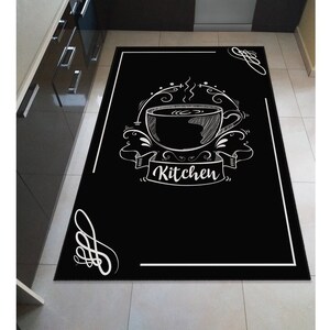 May include: Black and white kitchen rug with a stylised illustration of a coffee cup and the word "Kitchen" in a banner.