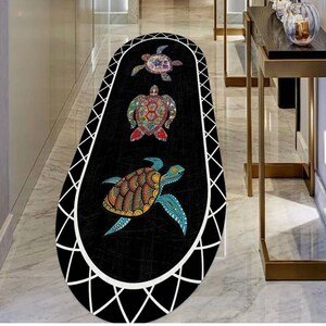 May include: An oval-shaped black rug featuring three colorful turtle designs. The turtles have intricate patterns in shades of blue, orange, green, and red. The rug is bordered with a white geometric design.