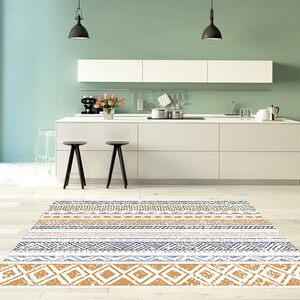 May include: A white, gray, and yellow patterned area rug with geometric designs. The rug is in a kitchen with white cabinets and a light green wall.