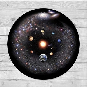 Puede incluir: Un objeto decorativo redondo y negro que presenta una representaci&oacute;n detallada del sistema solar y la V&iacute;a L&aacute;ctea. Se ven planetas, estrellas y galaxias, con un sol brillante en el centro. El objeto est&aacute; sobre un fondo negro.