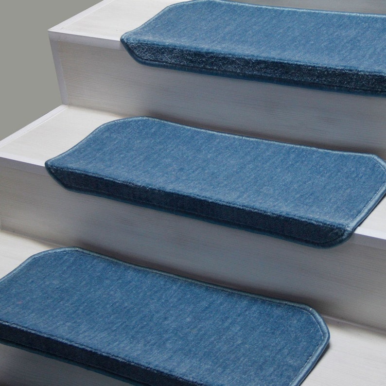 K&ouml;nnte beinhalten: Drei blaue Teppich-Treppenstufen mit einer strukturierten Oberfl&auml;che und einem hellblauen Rand. Die Stufen befinden sich auf einer wei&szlig;en Treppe.