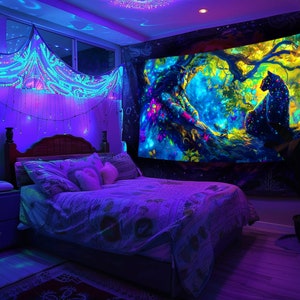 May include: A bedroom featuring a bed, a bedside table, and a tapestry on the wall. The tapestry is a vibrant psychedelic design with a black panther and a tree. The room is illuminated with blue and purple lights.