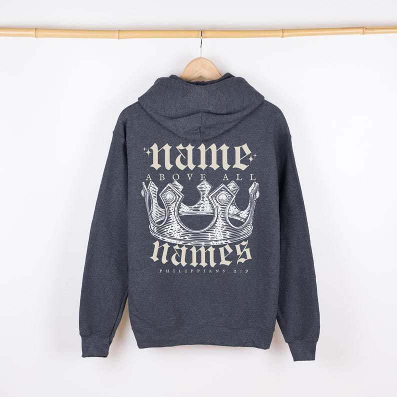 May include: A dark gray hooded sweatshirt with a white graphic print of a crown and the text "name above all names Philippians 2:9".
