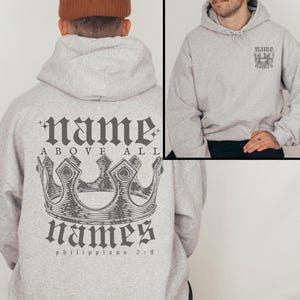 May include: Gray hooded sweatshirt with a crown and the text "name above all names" and "Philippians 2:9" printed on the back. The front of the sweatshirt has a small crown and the text "name names" printed on the left chest.
