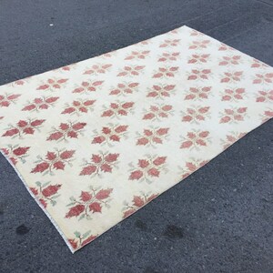 May include: A cream-colored rug with a repeating pattern of red and green floral designs.