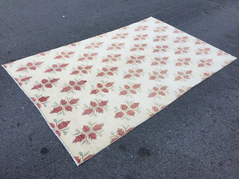 May include: A cream-colored rug with a repeating pattern of red and green floral designs.
