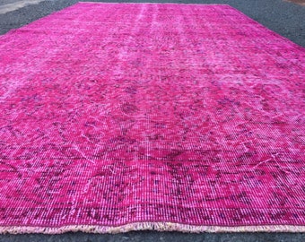 Könnte beinhalten: Ein großer, rechteckiger Teppich in leuchtendem Fuchsia. Der Teppich hat ein abgenutztes, Vintage-Aussehen mit dunkleren Bereichen und einem gefransten Rand. Das Muster ist eine Mischung aus vertikalen Linien und verblassten Details.