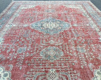 May include: A large rectangular area rug featuring a deep red background with intricate floral and geometric patterns in shades of blue, cream, and light green. The design includes a central medallion and a detailed border with repeating motifs.