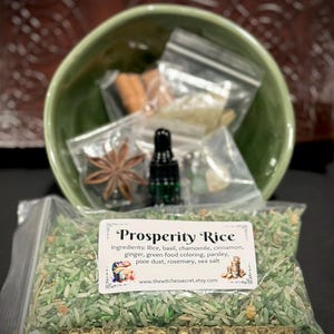 Peut inclure: Un bol vert contenant des petits sachets d'herbes, une badiane et un flacon compte-gouttes en verre foncé. Devant se trouve un sachet en plastique transparent de riz vert Prosperity avec une étiquette listant les ingrédients et le site www.thewitchessecret.etsy.com.