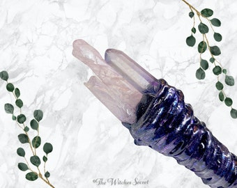 May include: A purple and silver wand with a clear, pink crystal at the top. The wand is wrapped in a sparkly, iridescent material.